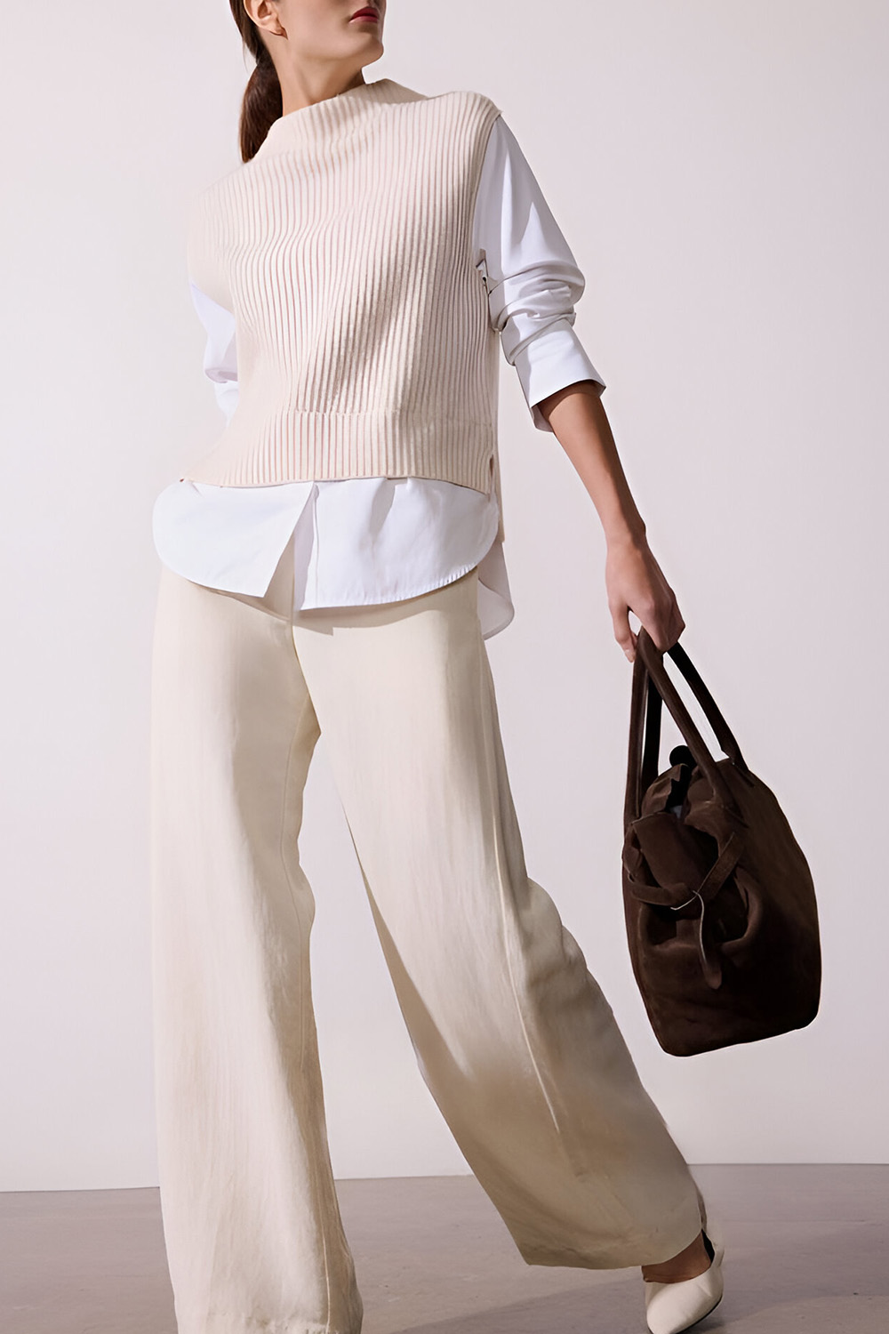 Sweater vest layered under long sleeve top with tailored trousers